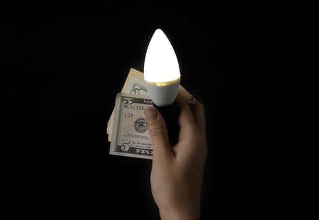 A hand reaching out to grab a stack of money, but the hand is blurry and indistinct. The stack of money is brightly lit, creating a sense of false promise.