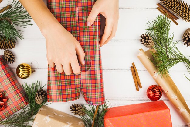 A close-up shot of hands expertly wrapping a Christmas gift with beautiful paper and ribbon, emphasizing the detail and care involved in gift-wrapping services.