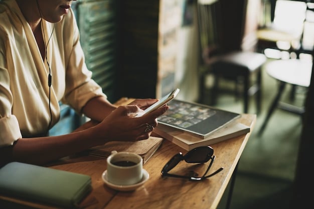 A close-up of a freelancer using a budgeting app on their smartphone while sitting at a coffee shop. The app displays charts and graphs illustrating income and expenses categories.