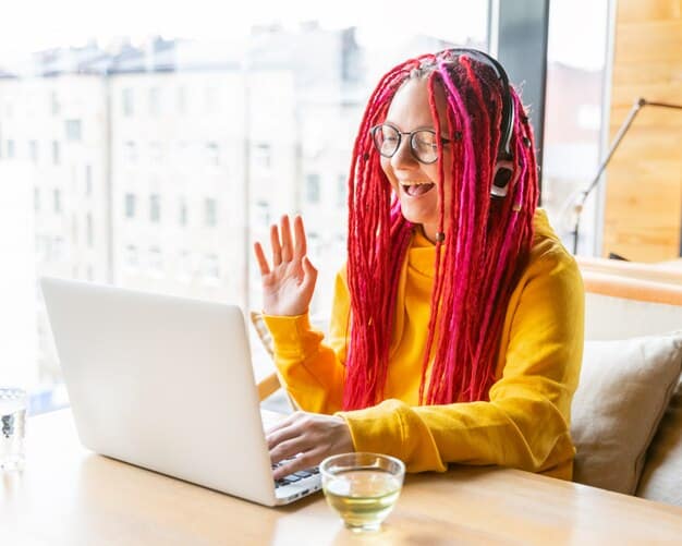 A freelancer sitting at a desk, smiling and typing on a laptop. The laptop screen displays a vibrant online community forum with various discussion threads related to freelancing.