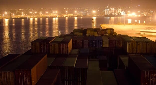 A visual representation of a congested global shipping route, with multiple cargo ships waiting near a port, showing long queues and container stacks.