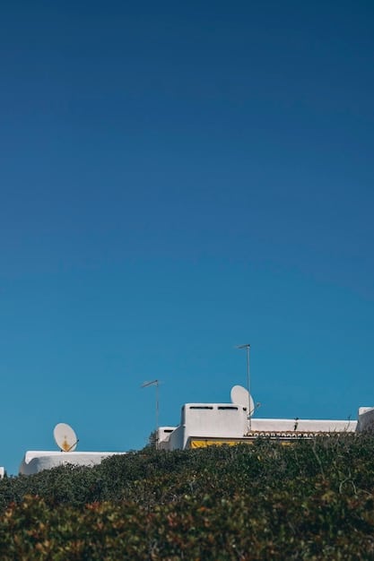 Solar panels on rooftops and a wind farm in the background under a blue sky, symbolizing renewable energy growth and clean technology.